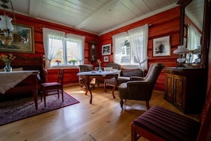 A room with wooden walls, a dining table with chairs, a sofa, a cabinet, and a mirror. - Roisheim Hotell (Lom)