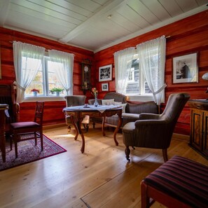 Une pièce aux murs en bois, avec une table en bois, deux chaises, un canapé et un meuble.