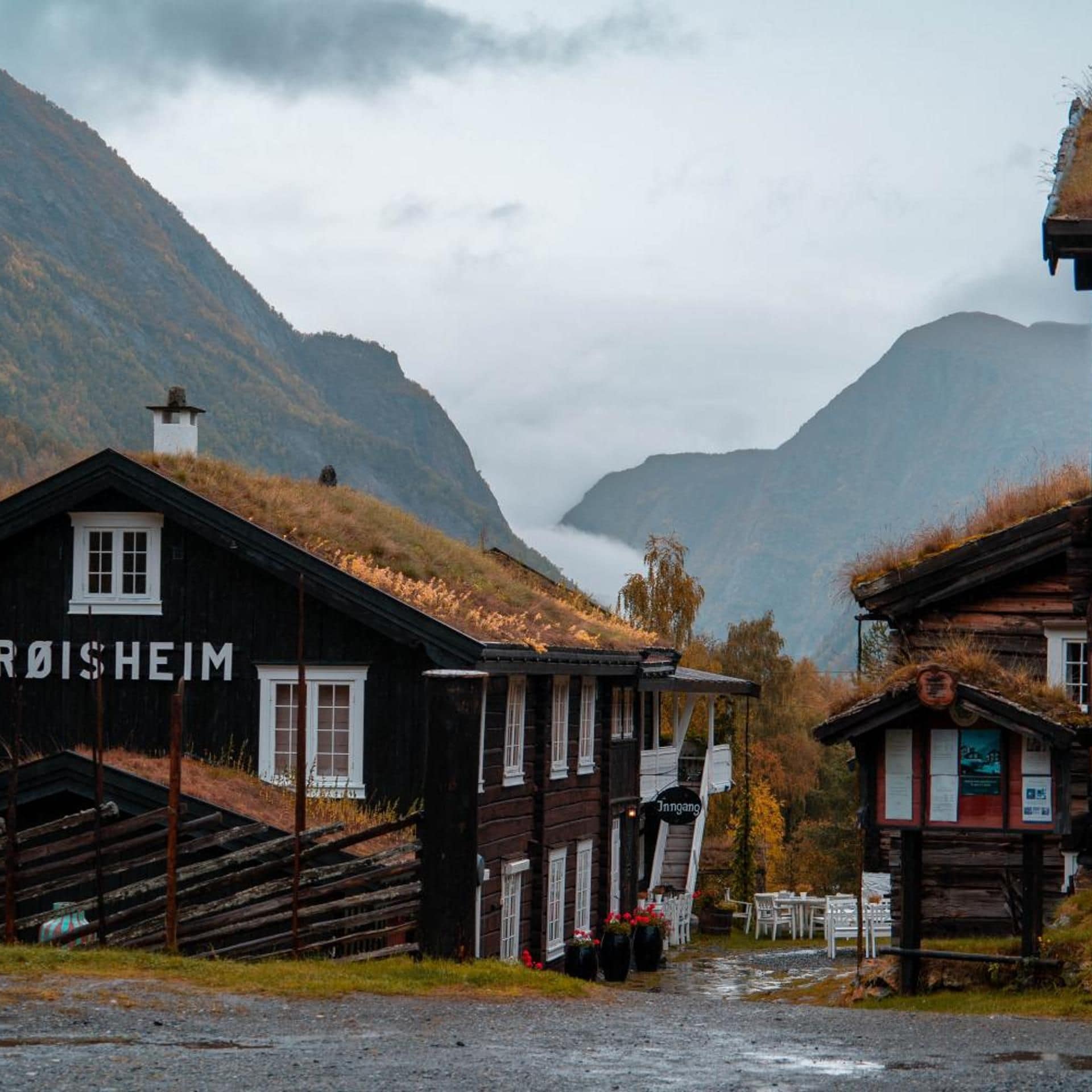 En enkel, lantlig byggnad med en skylt som visar texten ”RØISHEIM” och en mindre konstruktion med en skylt som visar texten ”Jiangang”.