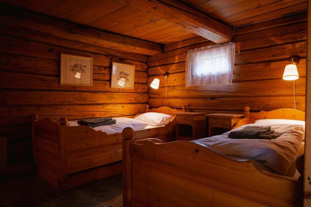 Een kamer in chaletstijl met twee houten bedden, een klein bureau en beelden in lijsten aan de muur.