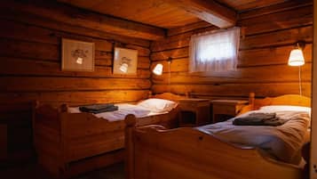 Een kamer in chaletstijl met twee houten bedden, een klein bureau en beelden in lijsten aan de muur.