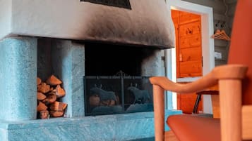 A room with a fireplace, a chair, and a patterned rug.