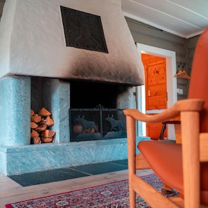 A room with a fireplace, a chair, and a patterned rug.
