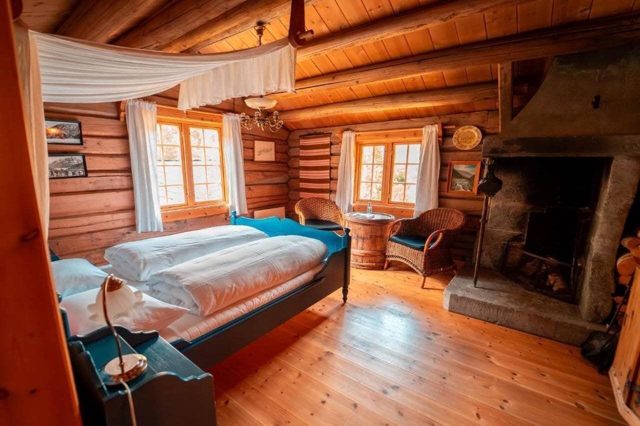 Een blokhutkamer met een bed, een open haard en een kleine tafel.