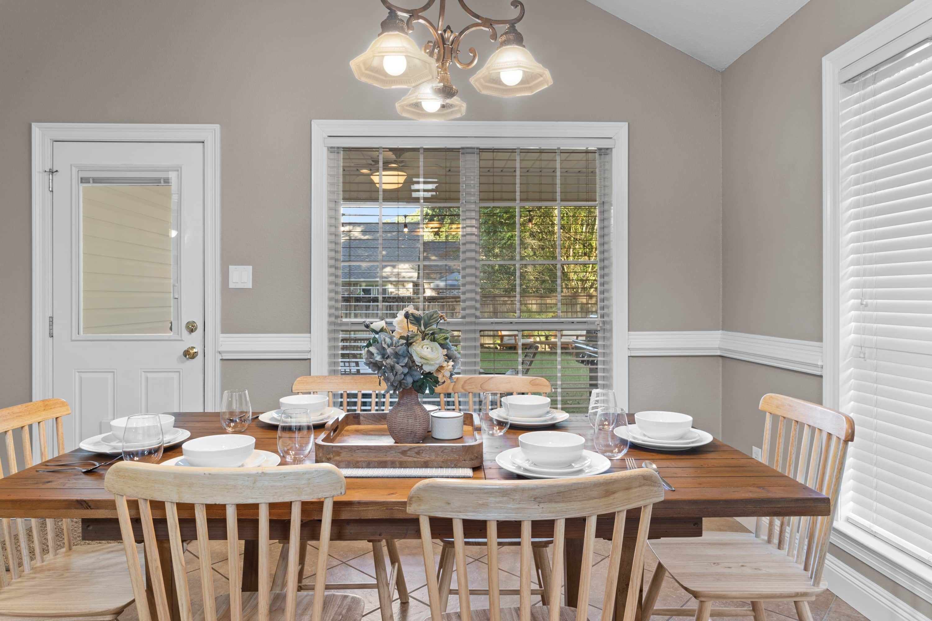 A dining room with a wooden table set for four, surrounded by wooden chairs.