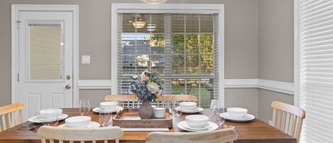A dining room with a wooden table set for four, surrounded by wooden chairs.