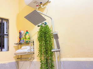 Un bany amb dutxa, un penjallotot per a tovalloles amb tovalloles pliegades i productes de neteja a l'estant.