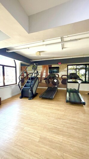 Een sportschool met loopbanden, een hometrainer en een roeimachine.