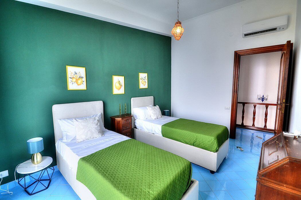 A room with two beds, a nightstand, a lamp, and a mirror.