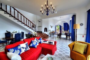 A spacious living area with a red sofa, yellow armchair, and a staircase leading to another level. - Villa Talassia: A charming two-story villa built sheer above the sea and with direct access to the sea, with Free WI-FI. (Massa Lubrense)