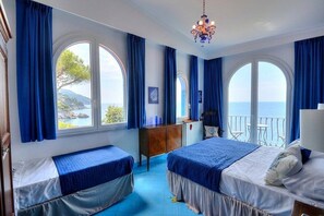 Una habitación con dos camas, un aparador de madera y vista al mar.