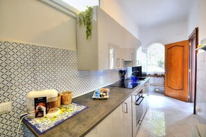 Una cocina moderna con encimera de mármol, armarios blancos y salpicadero estampado.