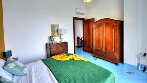 Un dormitorio con cama, armario de madera, mesita de noche y lámpara.