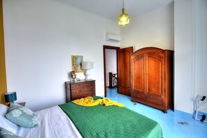 A bedroom with a bed, a wooden wardrobe, a nightstand, and a lamp. - Villa Talassia: A charming two-story villa built sheer above the sea and with direct access to the sea, with Free WI-FI. (Massa Lubrense)