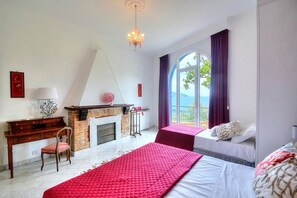 Ein Schlafzimmer mit Kamin, Schreibtisch und Blick ins Freie.