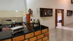 A kitchen with a black countertop, a brick accent wall, and a hanging light fixture.