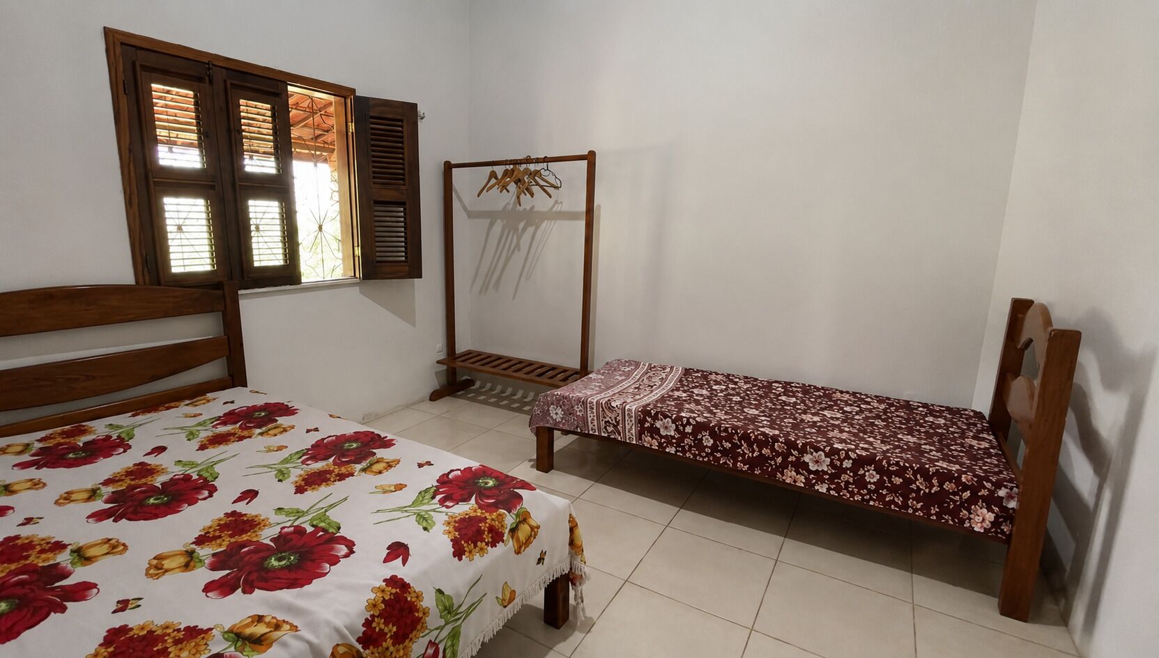 Un dormitorio con cama, una banca y una ventana con contraventanas.