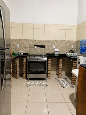 Una cuina amb forn integrat, nevera i dispensador d'aigua.
