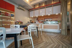 Un interior de restaurante moderno con sillas blancas, suelo de madera en espiga y una barra con productos alimenticios.