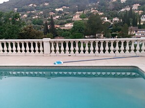 A swimming pool with a white balustrade and a mop on the edge. - Vrbo Property (Le Tignet)