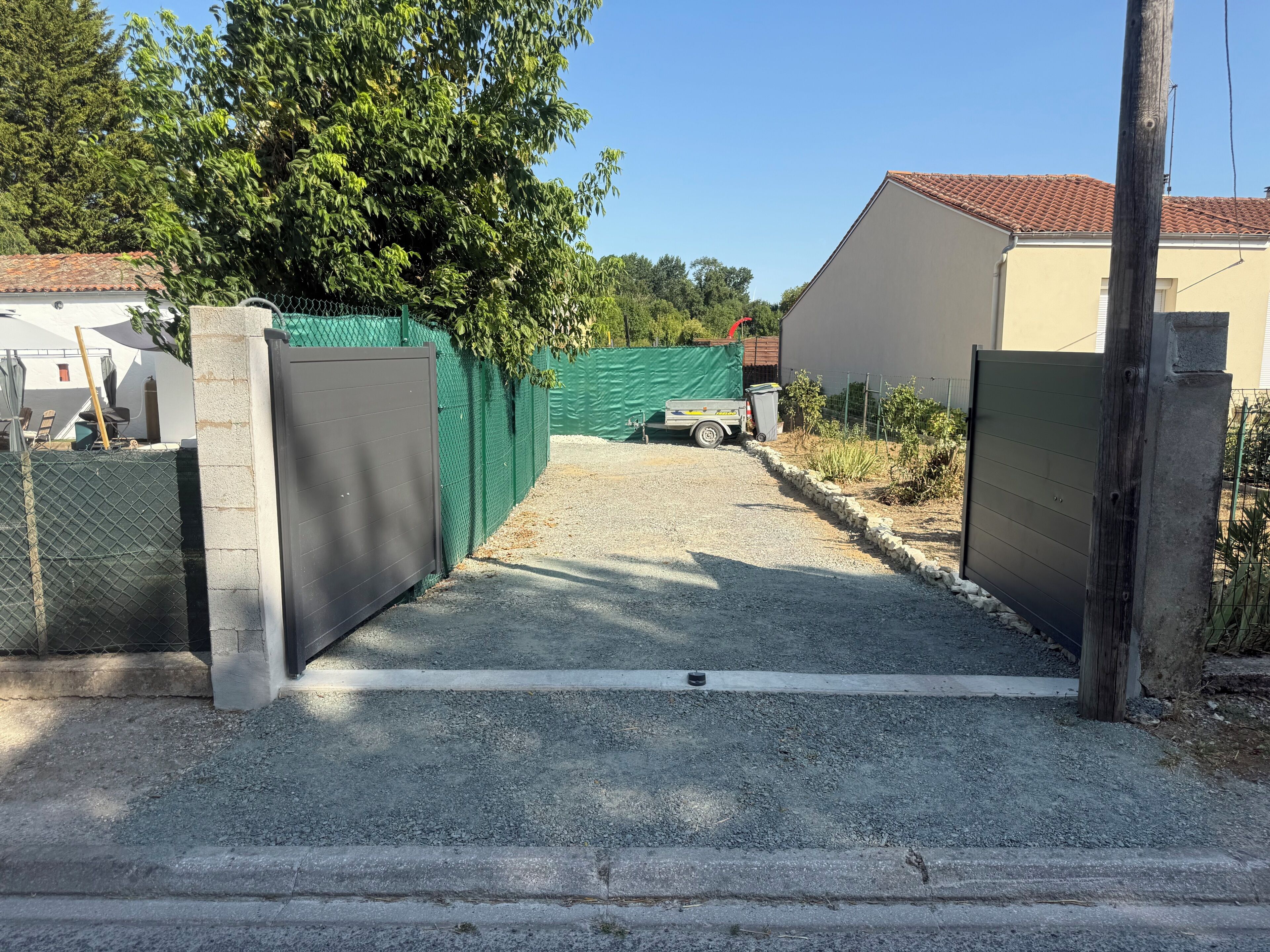 Een oprit met poort die naar een gebouw met tegels op het dak leidt.