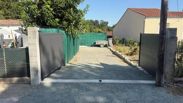 Een oprit met poort die naar een gebouw met tegels op het dak leidt.