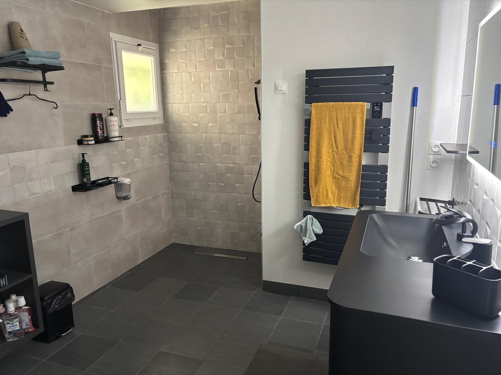 Une salle de bain moderne équipée d’une douche, d’un lavabo et d’un porte-serviettes.