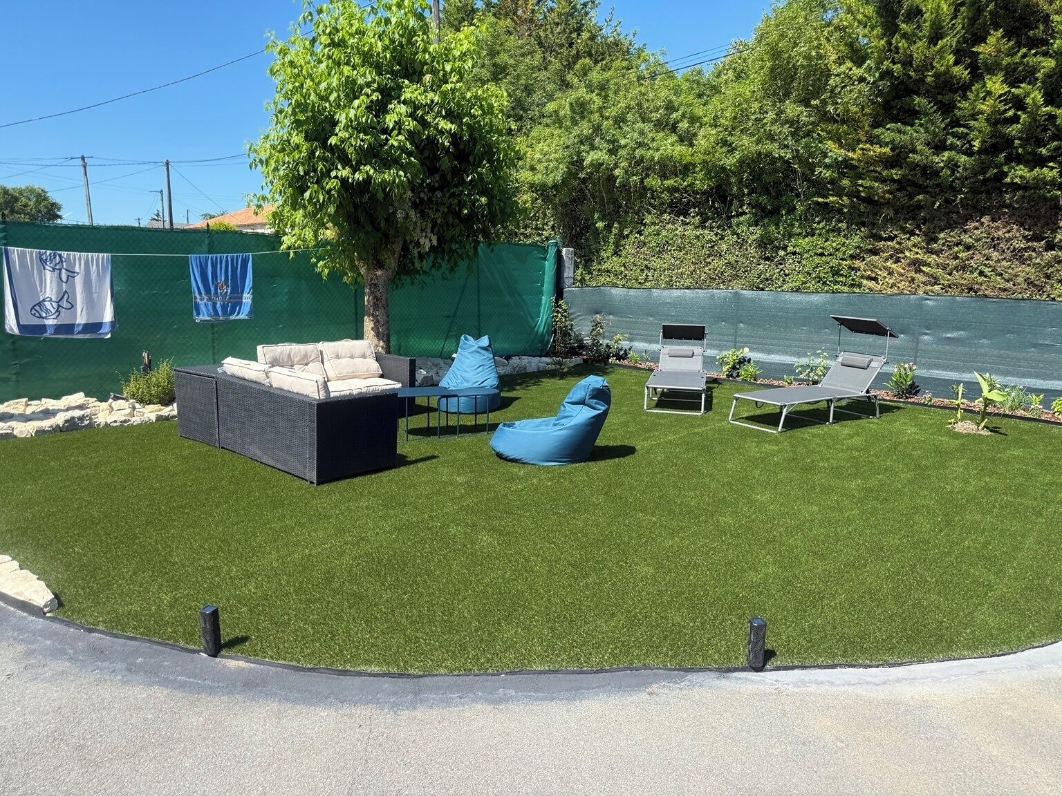 A patio with artificial grass, outdoor furniture, and a view of a body of water.