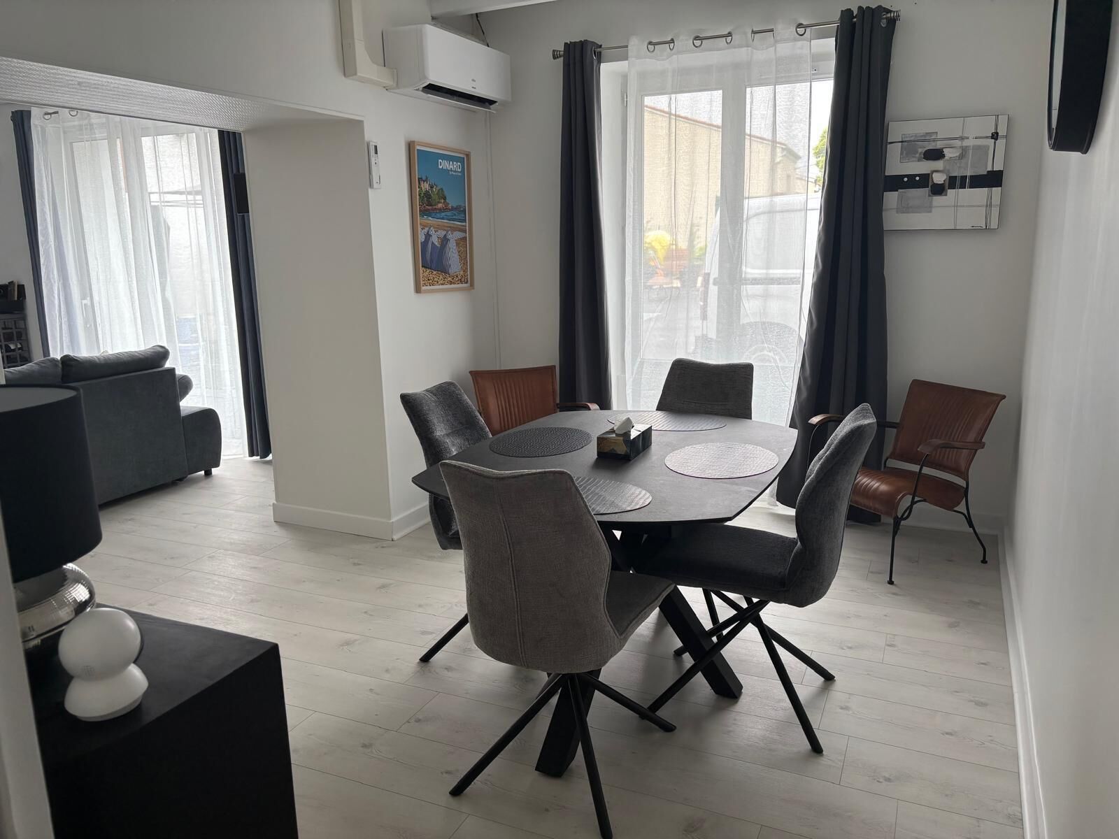 A modern dining area with a round table, grey upholstered chairs, and a black floor lamp.