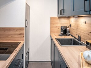 Eine moderne Küche mit Einbauofen, Kaffeemaschine und Spüle.