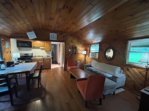 A cozy cabin interior with a dining area, kitchen, and seating space.