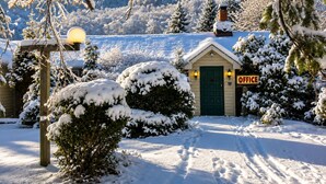 A snow-covered landscape with a small building labeled 'OFFICE' in the foreground, surrounded by snow-laden trees and a clear sky.