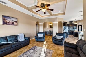 A spacious living area with a high ceiling, a ceiling fan, and a view into the dining area. - Private Pool + Spa + Fenced Backyard • Near North Padre Island | Graceland (Corpus Christi)