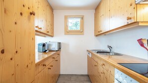 A compact kitchen with wooden cabinets, a microwave, a sink, and a dishwasher. - Collina 5i-02 by Interhome (Flims)