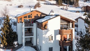 A modern multi-story building with a wooden facade, large windows, and a balcony area. - Collina 5i-02 by Interhome (Flims)