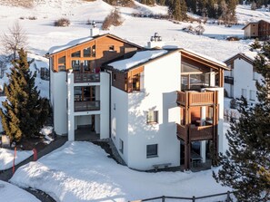 A modern multi-story building with a wooden facade, large windows, and a balcony area. - Collina 5i-02 by Interhome (Flims)