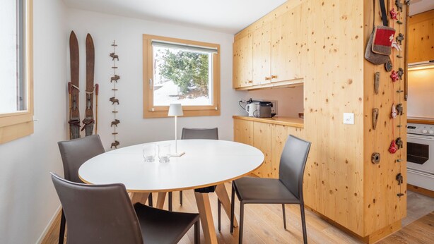 A compact kitchen with wooden cabinets, a round dining table, and chairs. - Collina 5i-02 by Interhome (Flims)