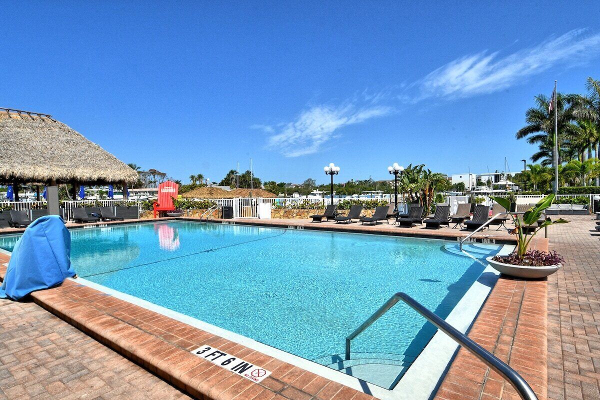 Une piscine dotée d’une structure avec toit de chaume, de chaises longues et surplombée d’un ciel dégagé.