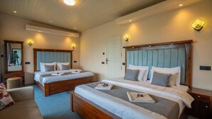 A hotel room with two beds, a sitting area, and a mirror.