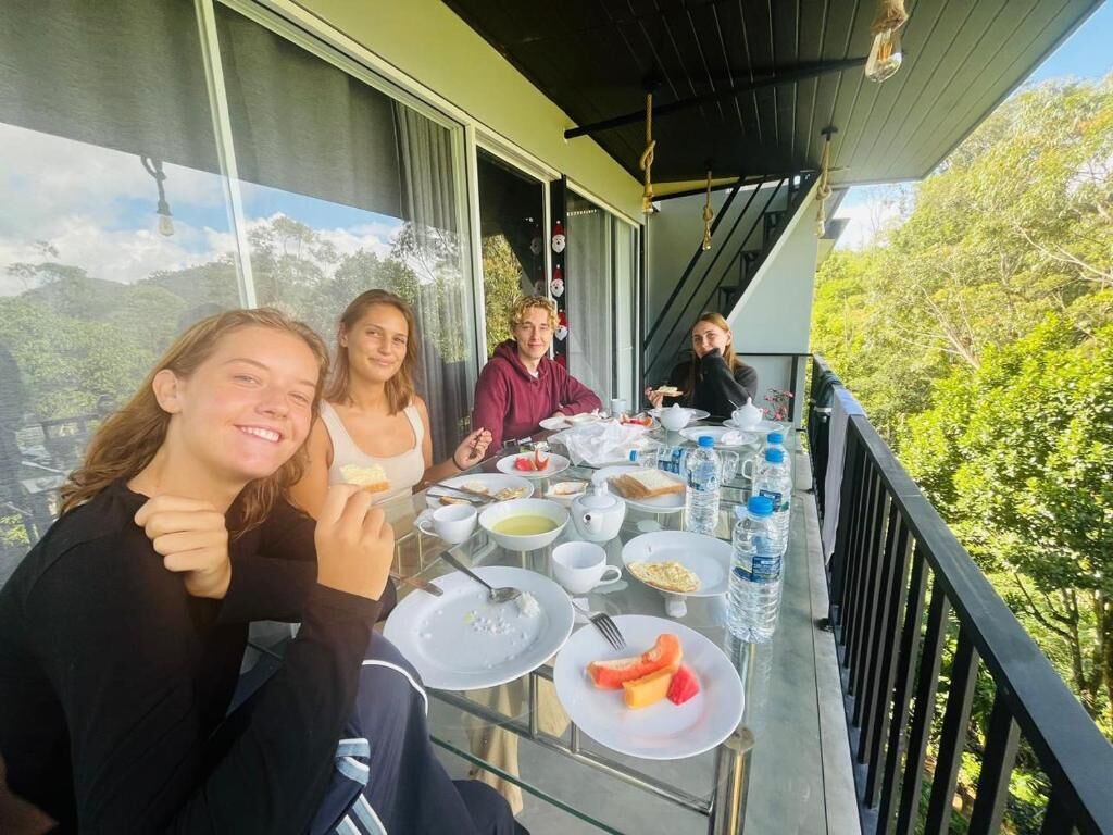 A dining area with a table set for four people, surrounded by glass railings with a view of greenery.