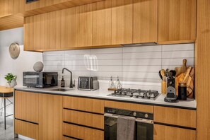 A modern kitchen with wooden cabinets, a microwave, toaster, gas stove, and a dishwasher.
