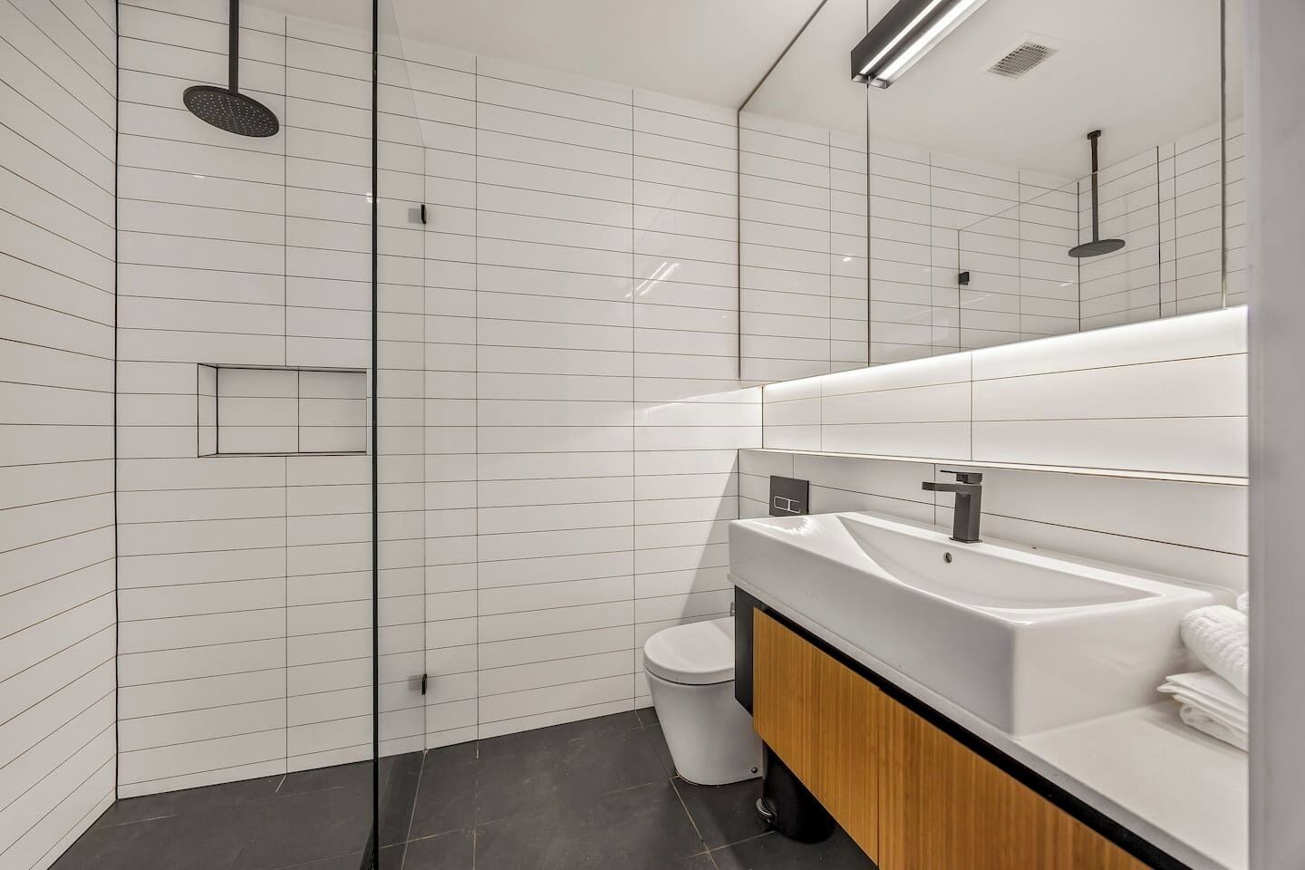 Une salle de bain moderne avec une douche à parois de verre, un lavabo blanc et des toilettes.