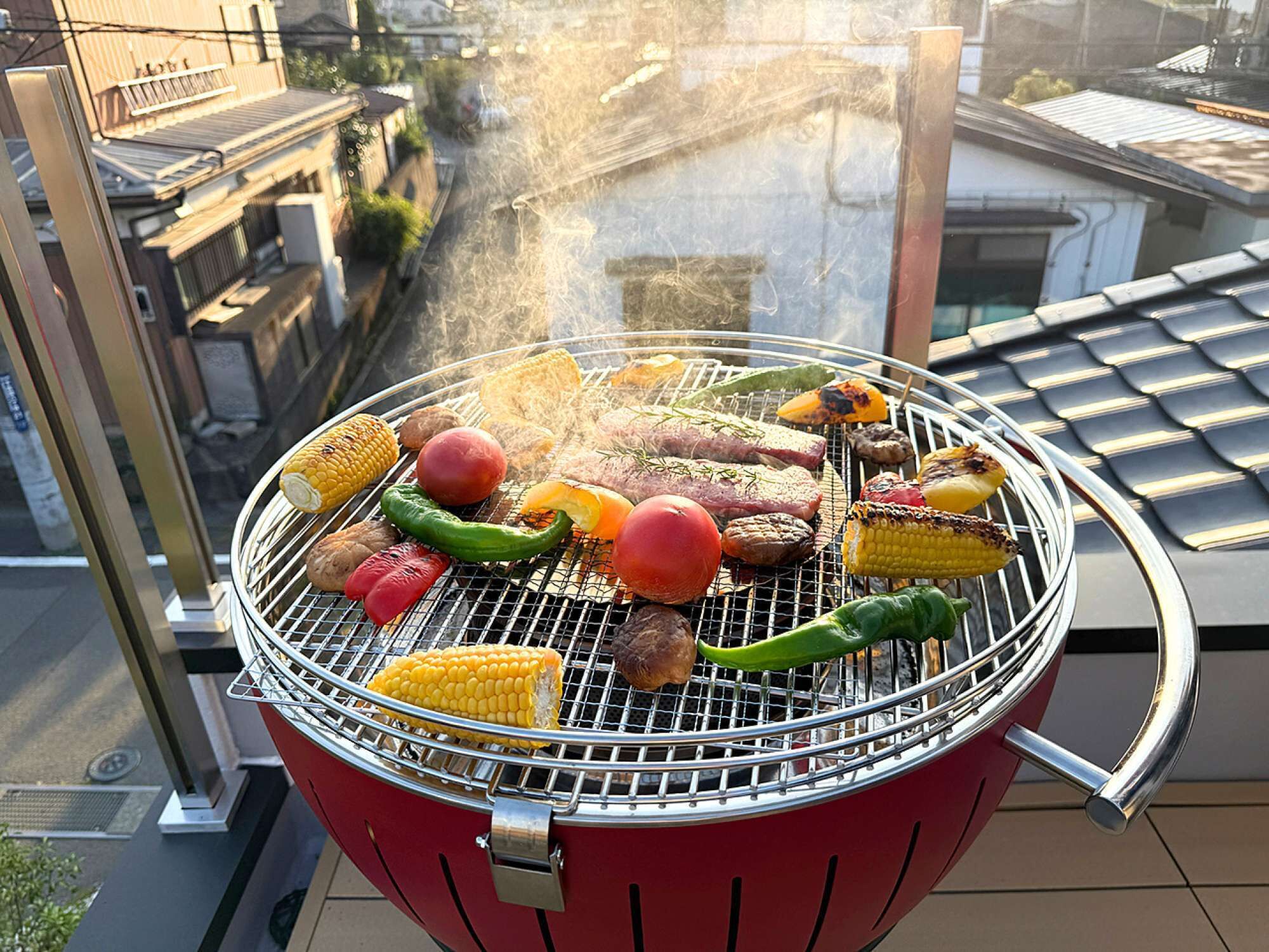 A rooftop barbecue grill with various vegetables and meats being cooked.