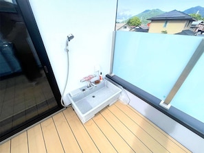 Un balcón pequeño con ducha integrada, una ventana y vistas a la montaña.