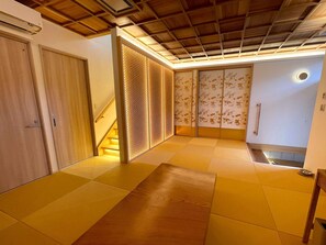 A hallway with a wooden ceiling, a sliding door with a floral pattern, and a small step leading to a lower level.