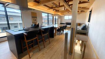 A modern kitchen with a bar area, wooden beams, and large windows.