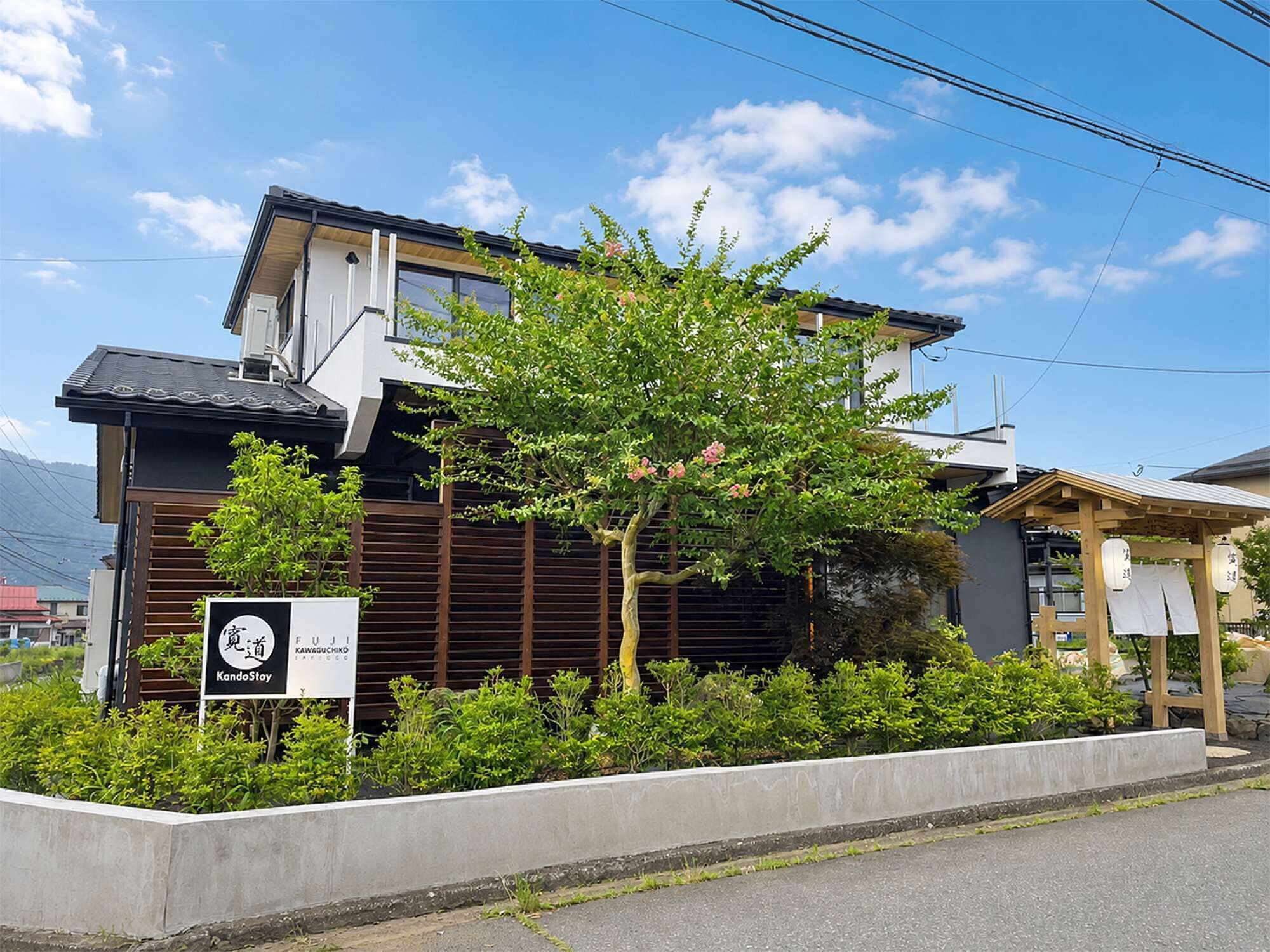 A modern building with a sign for KandoStoy, surrounded by greenery and a clear sky.