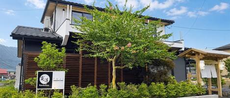 A modern building with a sign for KandoStoy, surrounded by greenery and a clear sky.