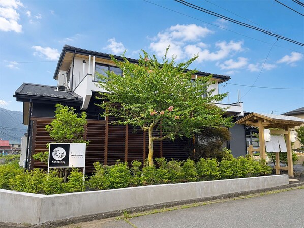 A modern building with a sign for KandoStoy, surrounded by greenery and a clear sky.