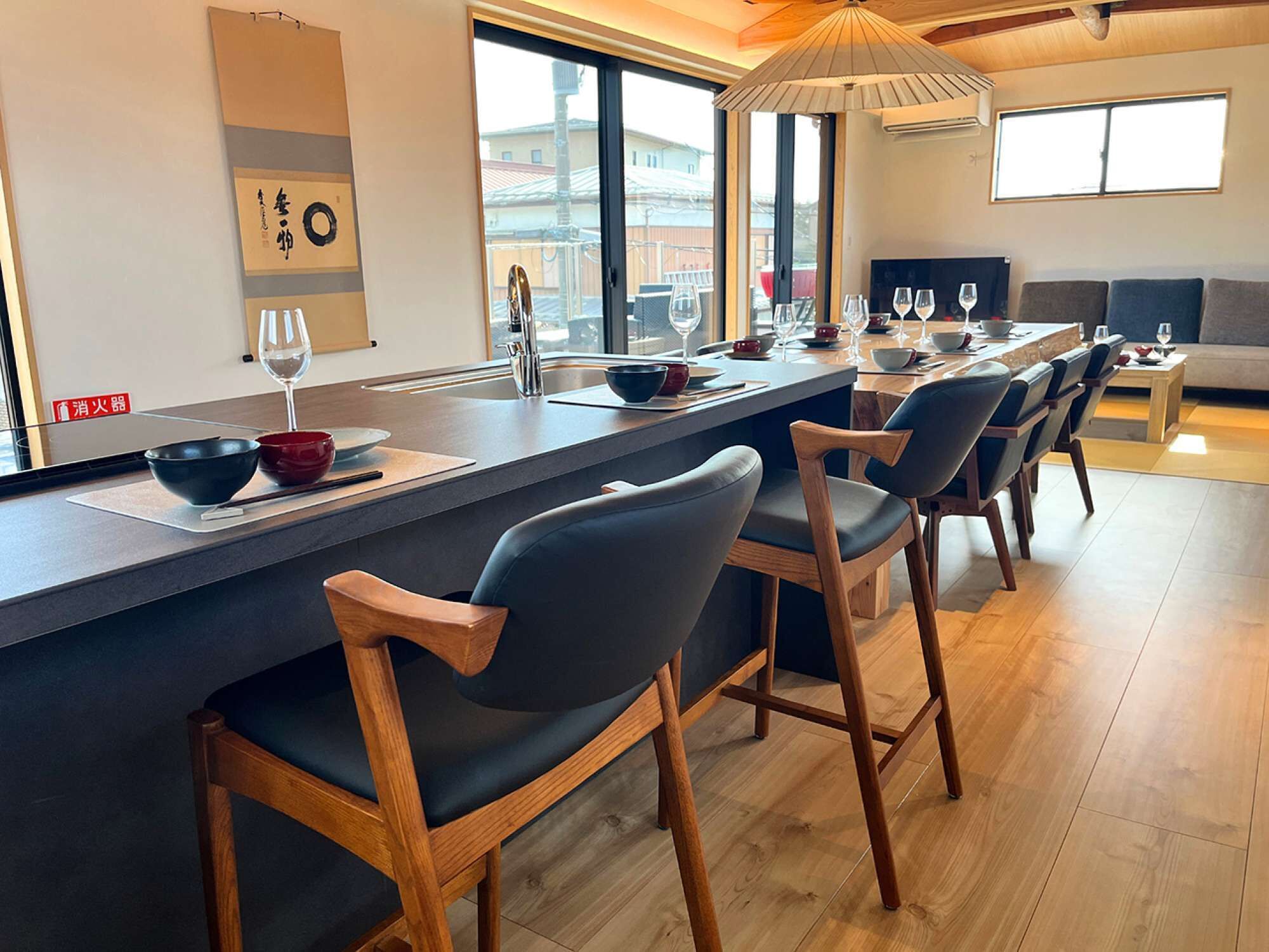 A modern kitchen with a central island, bar stools, and a dining area with a sofa and coffee table.